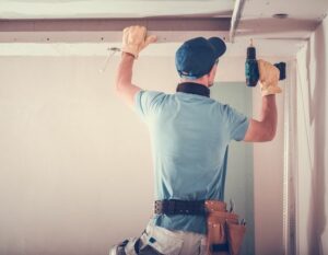Construction worker using power drill on ceiling