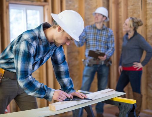 Man doing construction work while construction worker talks to designer